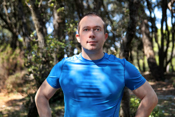 Handsome young fitness man wearing sportswear poses and enjoys a sunny day in beautiful landscape nature outdoors. Pretty guy, active, sportsman, cross fit, healthy lifestyle, fitness people concept.