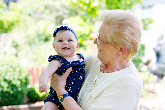 Cute little baby girl with grandmother on summer day in garden