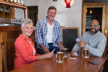 Happy friends playing cards while having glass of beer