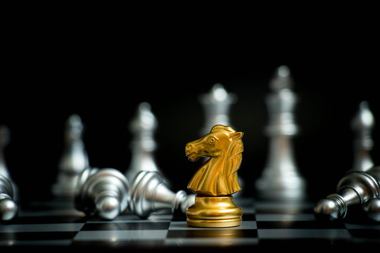 Gold horse in chess game face with the another silver team on black background (Concept for company strategy, business victory or decision)