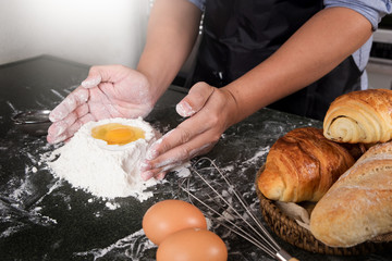 Fototapeta na wymiar Woman's hands knead dough with flour, eggs and ingredients. at kitchen.