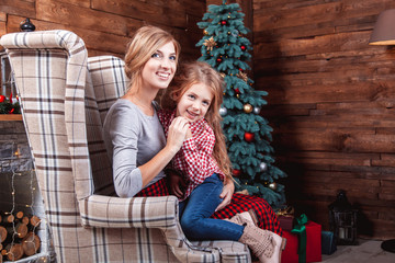 Beautiful happy mother with her daughter embrace in New Year interior with Christmas tree