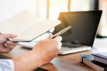 business men working on wooden desk(table) with notebook computer paper, pencil and hand in office, financial concept.