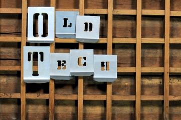 Word "OLD TECH" with stencils on old typefaces wooden container.