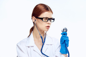 Beautiful young woman in glasses and in medical dressing gown holds a stethoscope on white isolated background, doctor, medicine