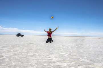 Salar de Uyuni in Bolivia with car. Girl jumping