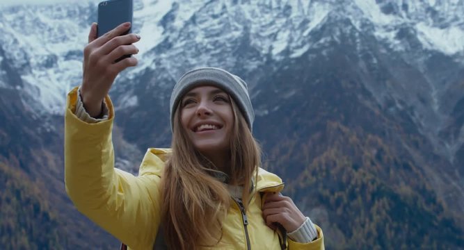 CRANE SHOT Beautiful Caucasian female hipster hiker making a selfie in front of Mont Blanc massif. 4K UHD RAW 60 FPS SLO MO