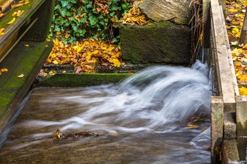 Old wooden water mill in the forest at autumn