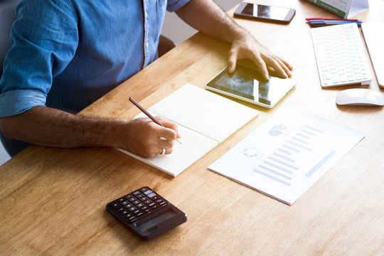 Calculate budget and business planning concept, people couting revenue and expenditure by using calculator and laptop  looking paper graph on desk in home office.