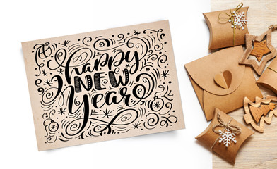 Lettering Happy New Year greeting card - text in vintage kraft paper on a white background. Flat lay, top view photo mockup