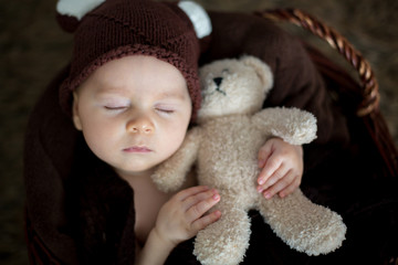 Cute three months old baby with bear hat in a basket, sleeping