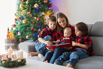 Happy family portrait on Christmas, mother, reading a book to her three children