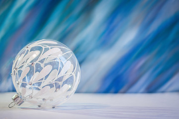 White glass decoration ball on a white and blue background. New Year and Christmas decoration.