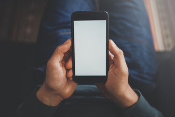 Close-up view of male hand holding modern smartphone with blank white screen. Blurred background.Blogger using mobile gadget. Horizontal mockup.