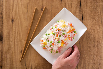 Chinese fried rice with vegetables and omelette on wooden table.Top view
