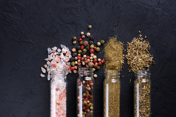 Mix of different spices in glass tubes on dark stone table flat lay top view