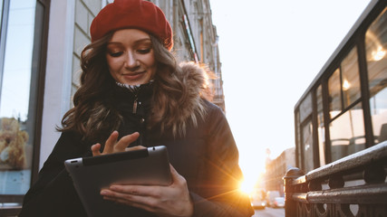 Young attractive girl with tablet in the sunset in the city. lifestyle portrait of young female using smart phone tablet for social media networking