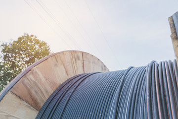 black wire  electric cable with wooden coil of electric cable under the sky.