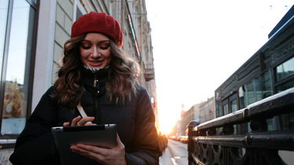 Young attractive girl with tablet in the sunset in the city. lifestyle portrait of young female using smart phone tablet for social media networking