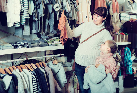 Pregnant mother and girl child choosing clothes