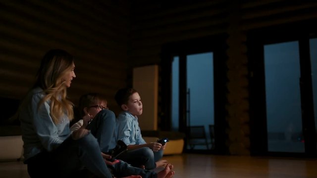 Beautiful mother with her son playing video games on gaming console in the living room of his house. Happy family in a country house.