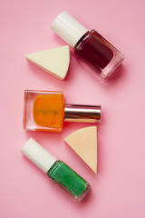  Colorful nail polish and sponge on a pink background. Flat lay