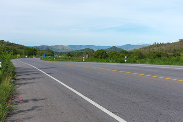 Stretched road along with trees and scenic view of mountain and blue sky