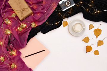 Romantic autumn mock up. Sheet of pink paper, yellow and orange leaves, pencils, cup of cappuccino and old camera.Top view. Flat lay.