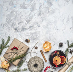 New Year composition, mulled wine cup, mandarins, fir branches, packing paper, cinnamon sticks, on a light rustic background, space for text, border