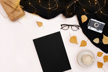 Romantic autumn mock up. Sheet of black paper, yellow and orange leaves, pencils, cup of cappuccino and old camera.Top view. Flat lay.