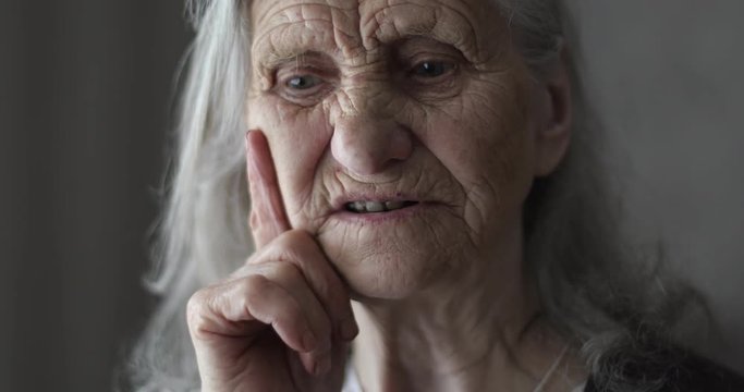Portrait of old woman with grey hair telling story.