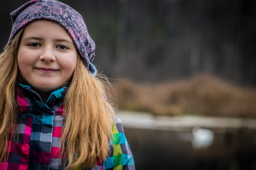 girl in coloured cap at autum like against dark brown forest