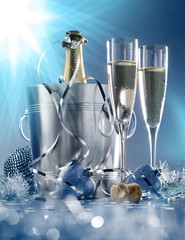 Two glasses and a cooler of champagne on bright blue background
