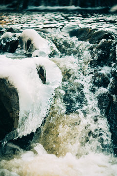 Aerial View Of The Wild Crystal Clear River, Flowing In The Rocky And Snowy Terrain, Winter Iceland