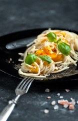 Noodles with sweet and sour sauce on a black plate close-up..