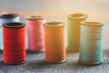 Different colour threads on splools on a piece of jeans fabric