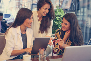 Young woman at cafe, checking credit card online.