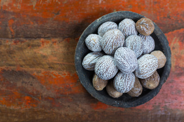 Tasty winter spice whole dried nutmeg, used as an ingredient in many dishes, eggnog, mulled wine, close up on old wooden table