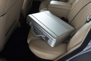 Luxury metal briefcase on a vinage car back seat.
