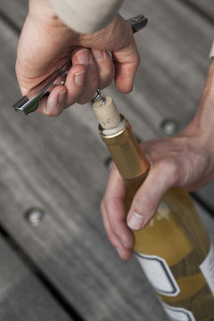 hand opening a wine bottle with a corkscrew