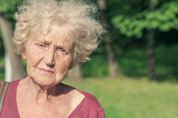 Angry sad elder woman in the park
