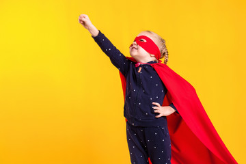 Funny little power superhero child girl in a red raincoat and a mask. Superhero concept.