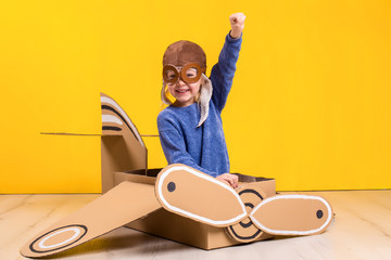 Little dreamer girl playing with a cardboard airplane. Childhood. Fantasy, imagination.