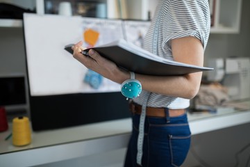 Mid section of female designer holding book