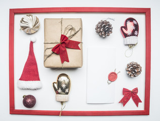 frame, Christmas or New Year composition, Santa Claus hat, lollipops, gift in a box with a bow, red packing paper, lined on a white background, top view, flat lay
