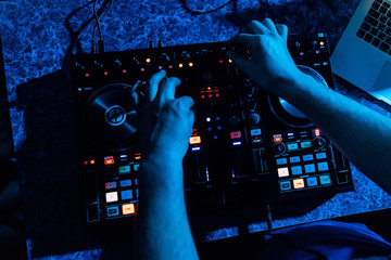 Fototapeta na wymiar mixer and DJ booth in nightclub with hands in night club on party with dark blue background