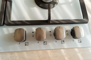 Four metal handles of gas cooker panel, top view.