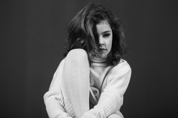 Little beautiful girl with brown hair in a light sweater and a skirt of tulle. Studio. A princess poses for a photographer.
