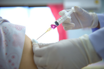 Soft focus nurses are vaccinations to patients using the syringe.Doctor vaccinating women in...