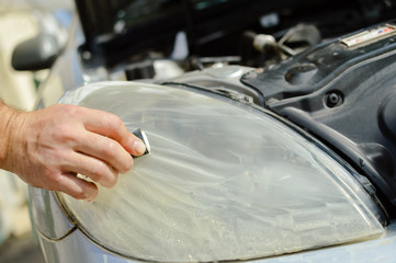Automobile industry. Close up on car detail - male hand polish in auto repair shop background. Professional person during mechanical maintenance, industrial part transport renovation